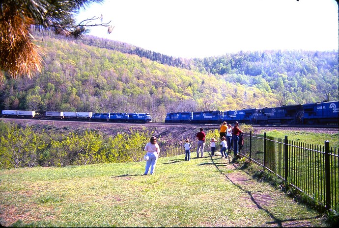 CR. East TV train led by B36-7 #5038 passes west freight led by SD45-2 #6665 at Horseshoe Curve. May 1986