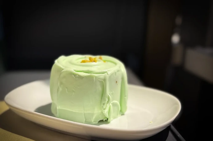 A green mousse dessert on a white plate with a garnish on top