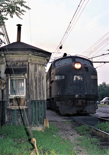 NJT E-8 # 4328, (ex- PRR #5885 blt 3-50), in Penn Central paint. E-8 is leaving South Amboy, NJ for Bay Head, NJ. John Street crossing guard house to left. Sept 1980