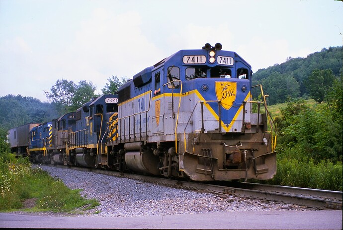D&H. GP39-2 #7411, GP38-2 #7321, C-420 #412 & CRS-36 #451 Belden Tunnel Road crossing south of Belden, NY, Aug 1984