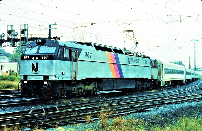 NJT. E-60 # 967 on a passenger train with Comet cars at South Amboy, NJ. Cloudy day in  April 1987