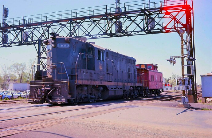 CNJ FPSD-37 #1523 with caboose #91528 heading west to High Bridge at Anderson Ave crossing. Raritan, NJ.  June 1974