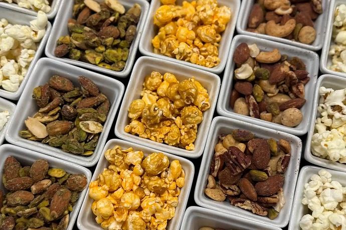 Assorted bowls containing different snacks including popcorn nuts and seeds arranged together